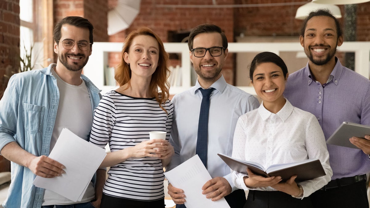 Jobbewerber mit Bewerbungsunterlagen in der Hand lachen in die Kamera